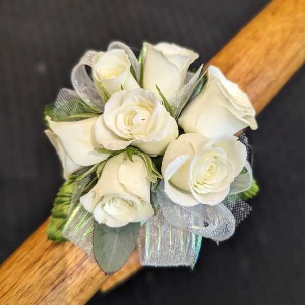 Small cluster of white roses with silver ribbon arranged as a wrist corsage