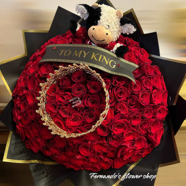 Large round bouquet of red roses with a plush cow, gold crown, and 'To My King' ribbon on black and gold wrap.