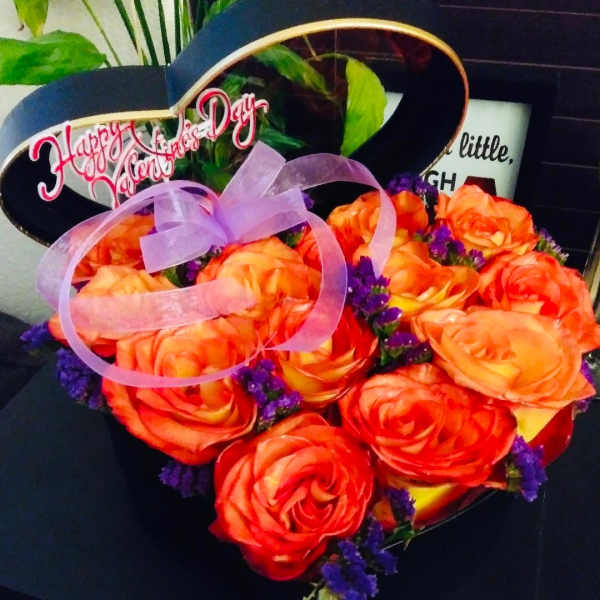 Heart-shaped bouquet of orange roses with a purple ribbon and "Happy Valentine's Day" sign