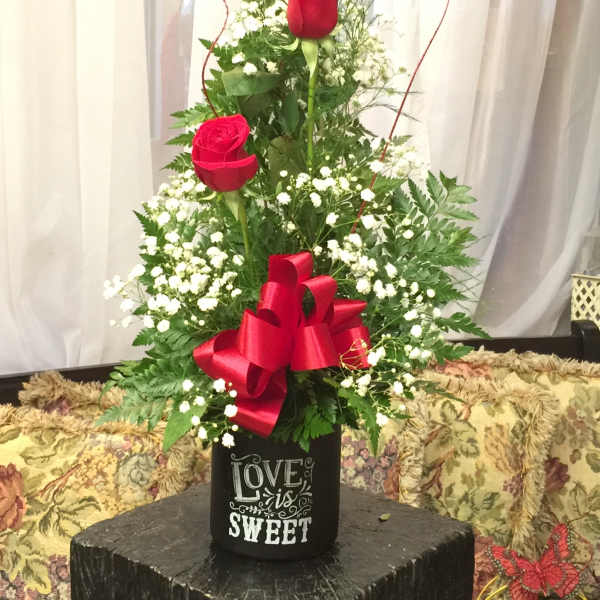 Tall arrangement of red roses with baby's breath in a black container
