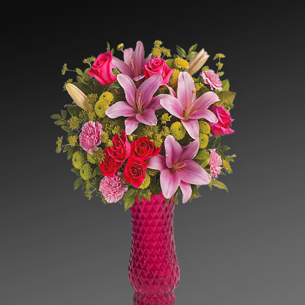 Pink lilies and roses arranged in a tall pink vase