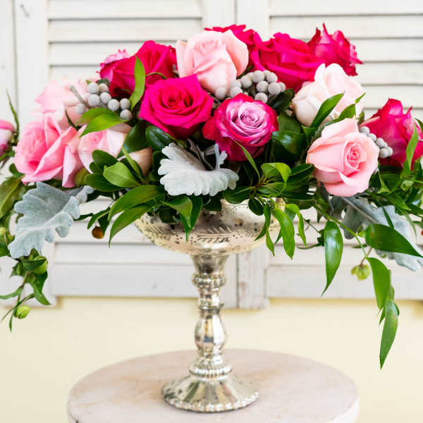 Pink and hot pink roses arranged in a silver pedestal vase