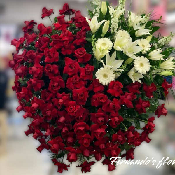Large heart-shaped arrangement of red roses with white lilies and gerberas on one side