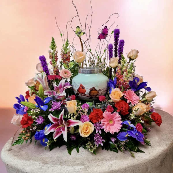 Colorful floral arrangement around a painted ceramic urn with bird design