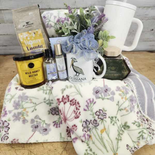 Gift basket with a floral blanket, mug, candle, honey, and lavender items
