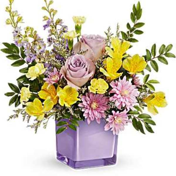 Lavender and yellow mixed flower arrangement in a purple glass vase