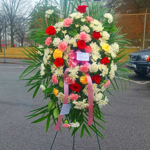Large standing floral wreath with red, pink, and white flowers on an easel