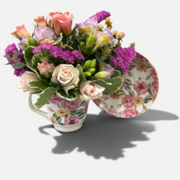 Floral arrangement in a floral teacup with pink and lavender blooms