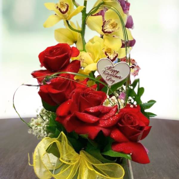 Red roses with tall yellow orchids and a Valentine heart pick