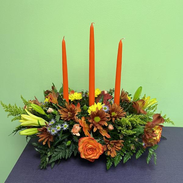 Orange candle centerpiece with mixed flowers and lilies