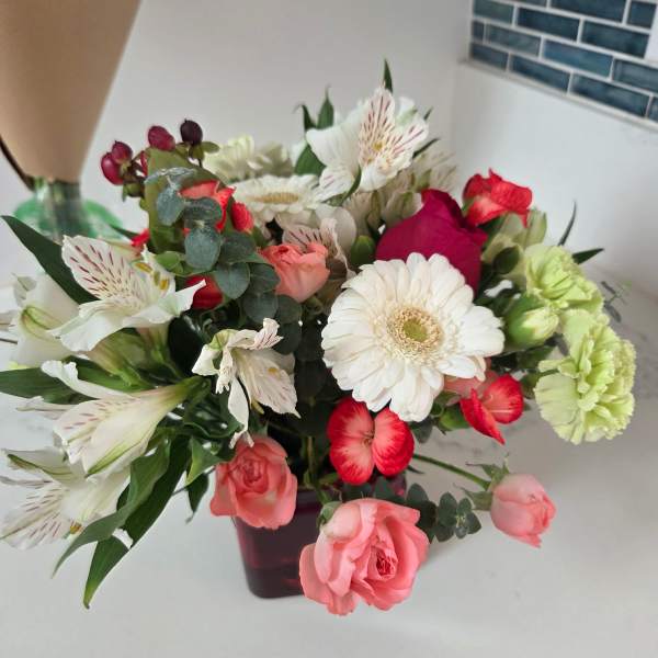 Mixed bouquet of pink, white, and red flowers in a dark vase