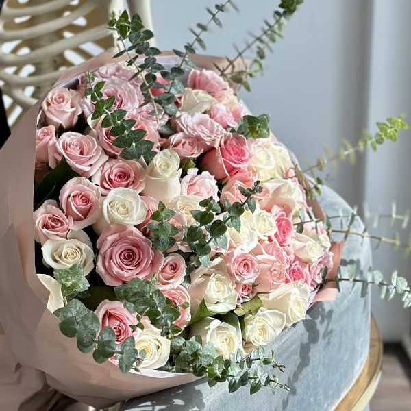 Bouquet of pink and white roses with eucalyptus in pink wrapping