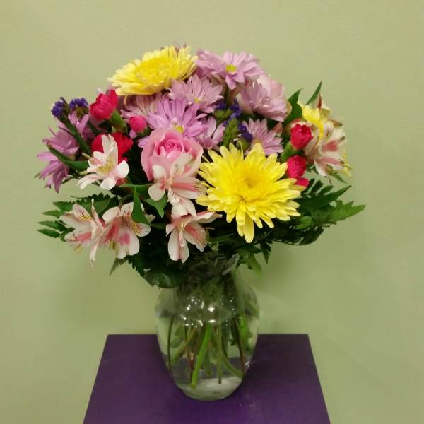 Mixed bouquet of daisies, roses, and alstroemeria in a glass vase