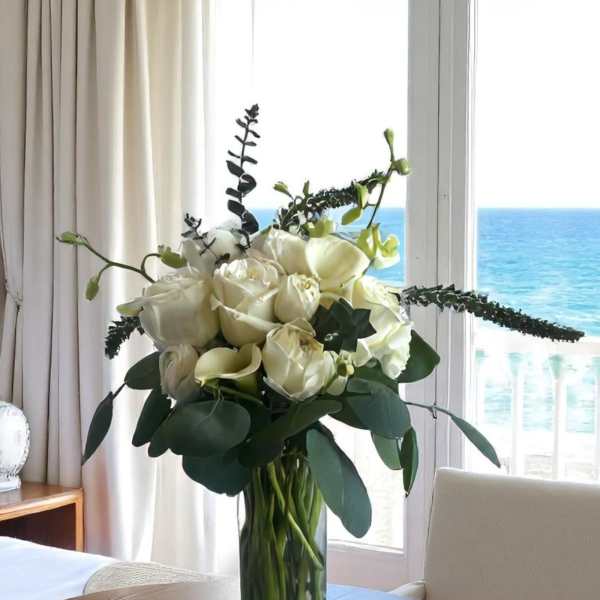White roses in a clear glass vase on a table