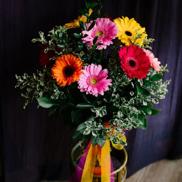 Colorful gerbera daisy bouquet in a glass vase with ribbon