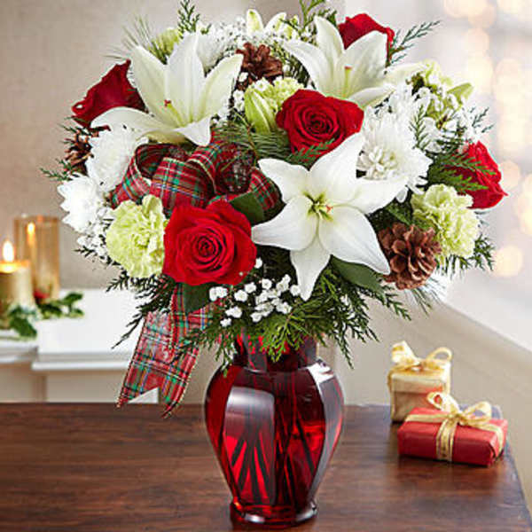 Red roses and white lilies in a red glass vase with plaid ribbon