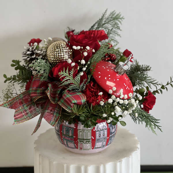 Red roses in a festive holiday arrangement with ornaments in a decorative pot