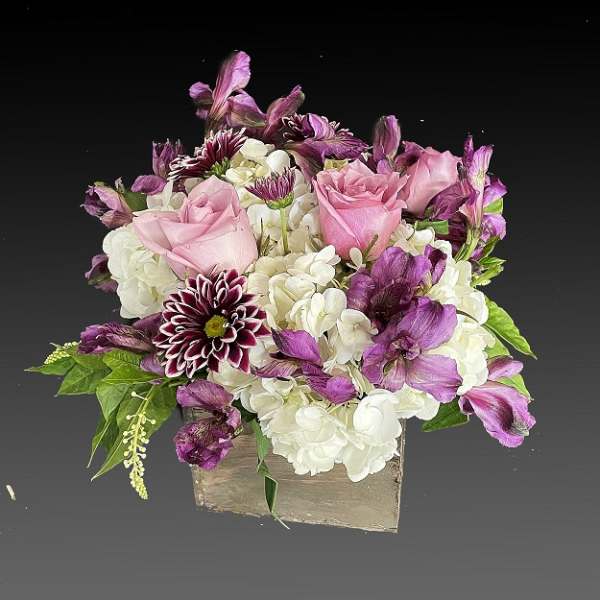 Pink roses and white hydrangeas with purple flowers in a square container