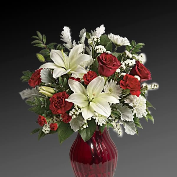 Red roses and white lilies arranged in a red glass vase