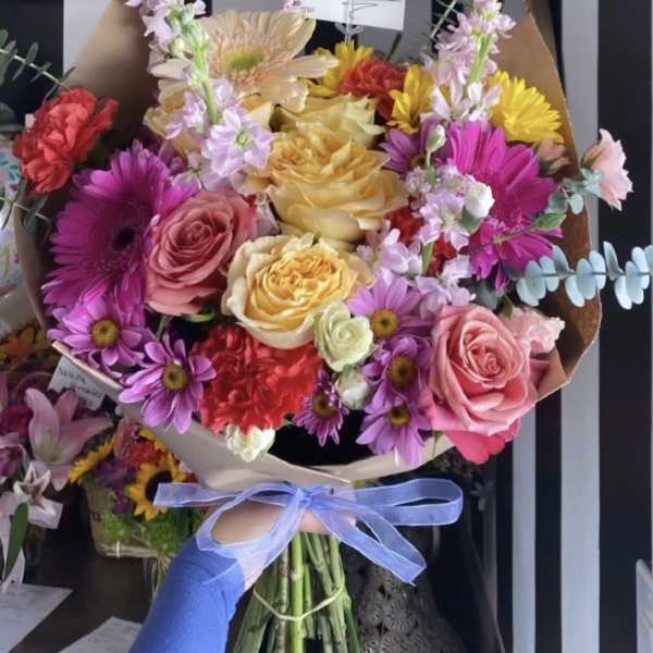 Colorful bouquet of roses and daisies tied with a blue ribbon