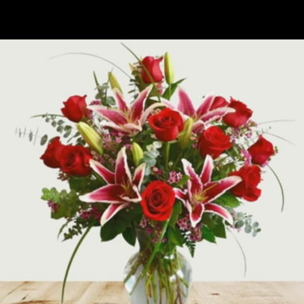 Bouquet of red roses and pink lilies in a clear glass vase