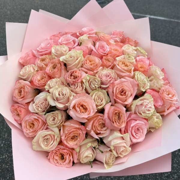 Large bouquet of pale pink and peach roses wrapped in pink paper