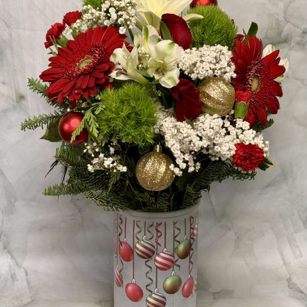 Red and white floral arrangement in a decorated cylindrical container