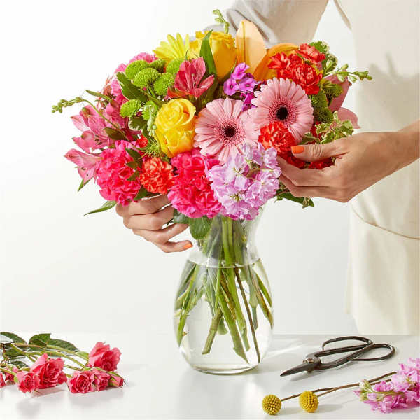 Colorful mixed bouquet in a clear glass vase with pink and yellow blooms