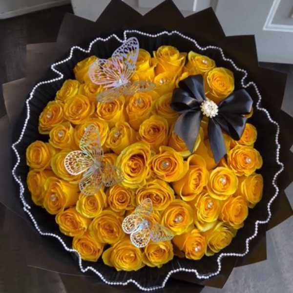 Bouquet of yellow roses with butterfly decorations and a black ribbon