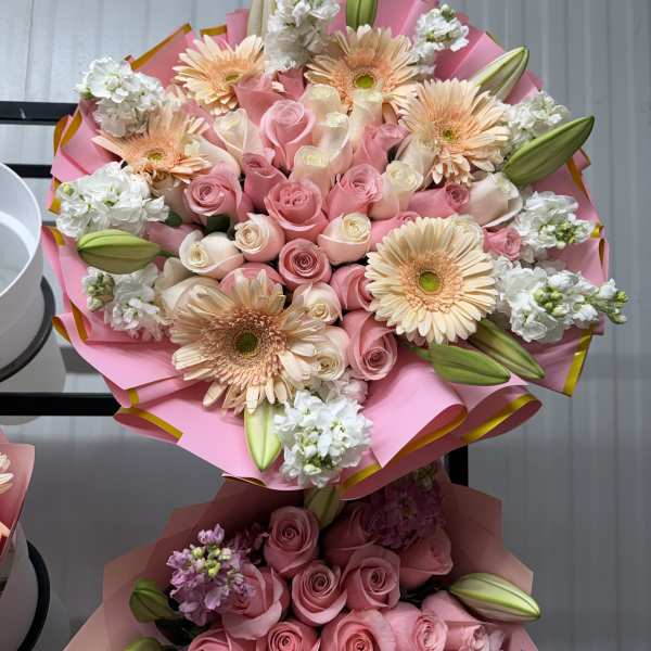 Pink and peach bouquet with roses, gerbera daisies, and lily buds