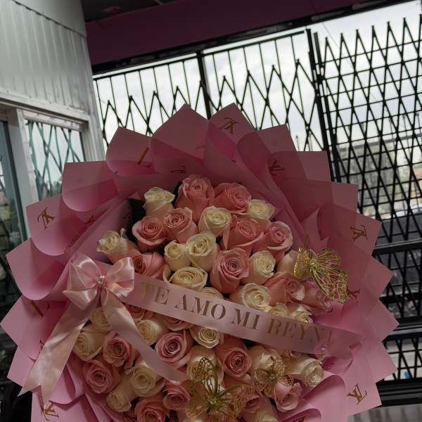 Pink and cream rose bouquet wrapped in pink paper with a ribbon