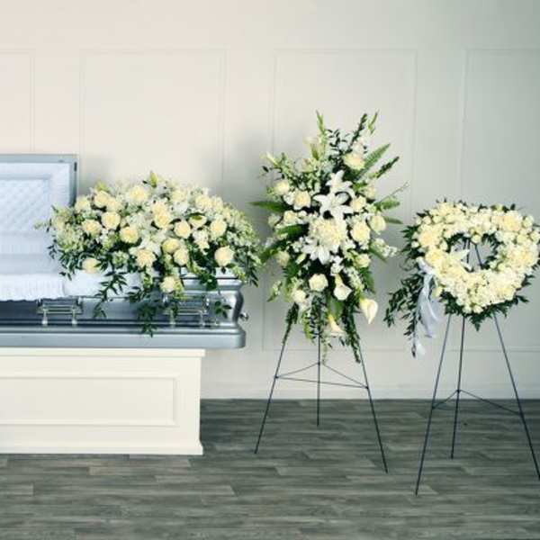 White floral funeral casket spray with matching wreaths and standing sprays