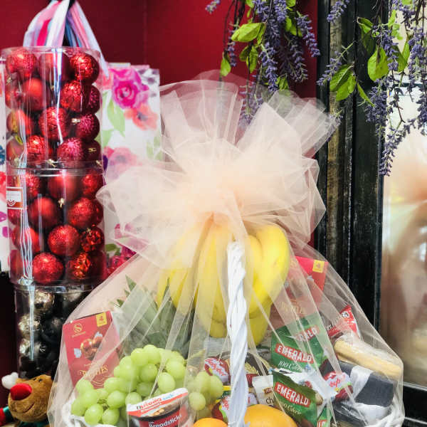 Fruit and snack gift basket in a white wicker basket with tulle wrap