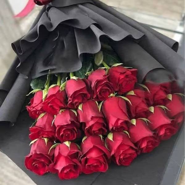 Bouquet of red roses wrapped in black paper with a burgundy bow
