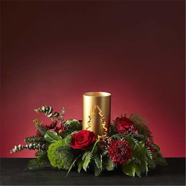 Red roses and holiday greenery around a gold candle holder