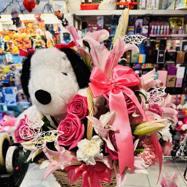 Pink lily and rose basket with a plush Snoopy toy and ribbon bows