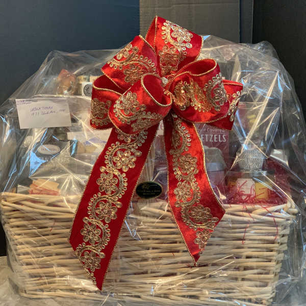 Gift basket wrapped in clear plastic with a large red decorative bow