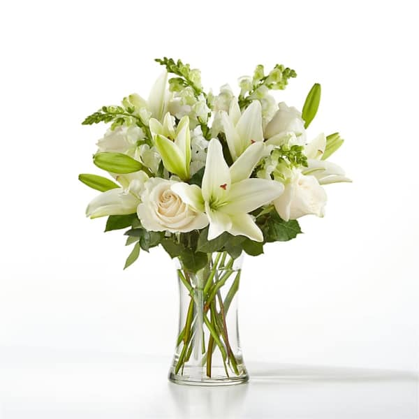 White lilies and roses arranged in a clear glass vase