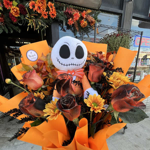 Bouquet of orange and black roses with a plush skull face topper