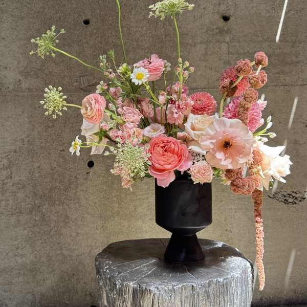 Pink and peach mixed flowers arranged in a black vase