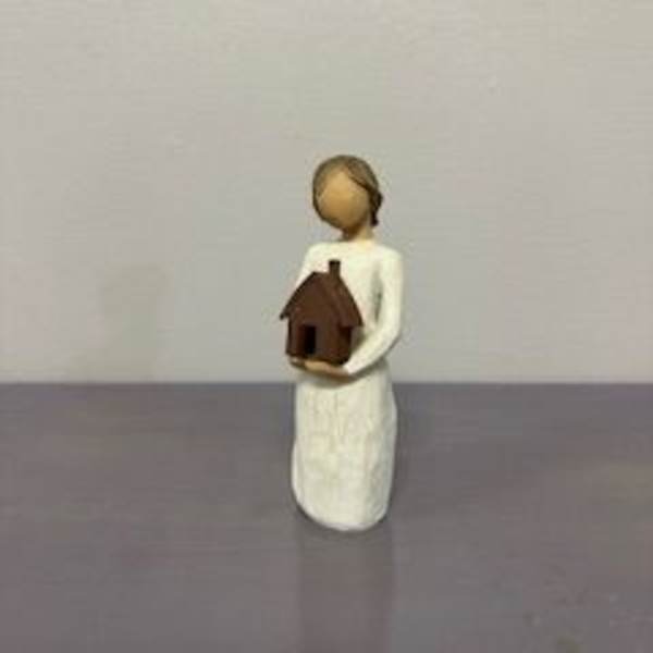 Small figurine of a person holding a tiny house