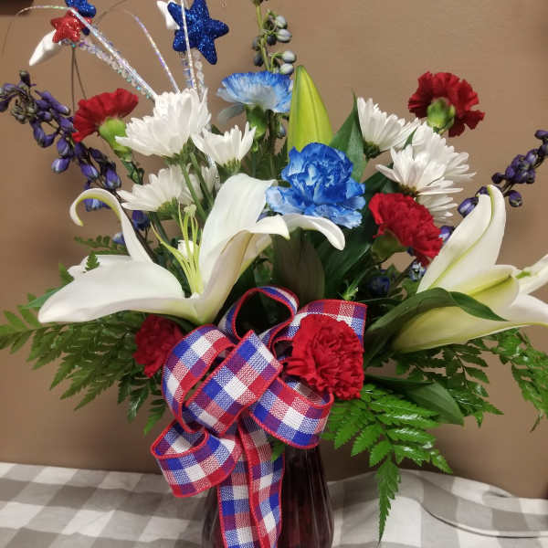 Bouquet of white lilies, red and blue carnations, and white daisies in a vase