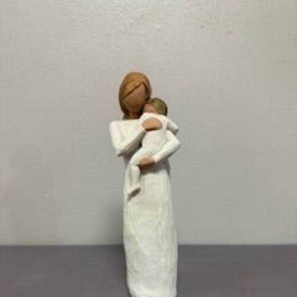 Small figurine of a woman holding a child, in white clothing