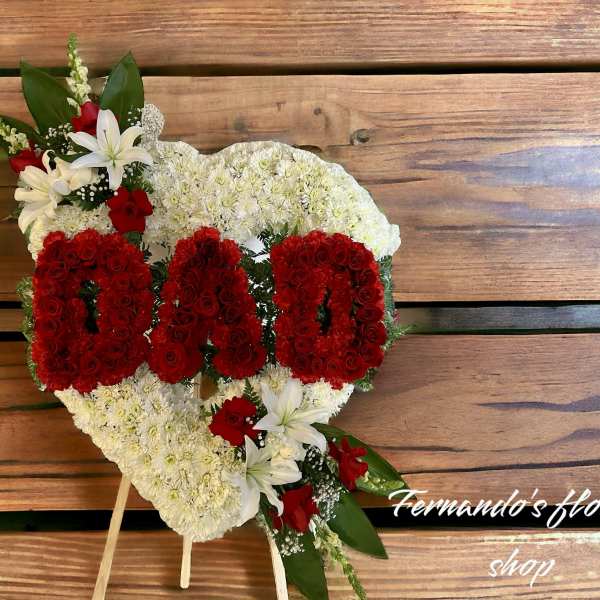 Heart-shaped white floral tribute with red 'DAD' letters on a wooden easel