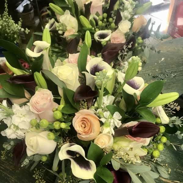Bouquet of cream roses, calla lilies, and dark purple tulips