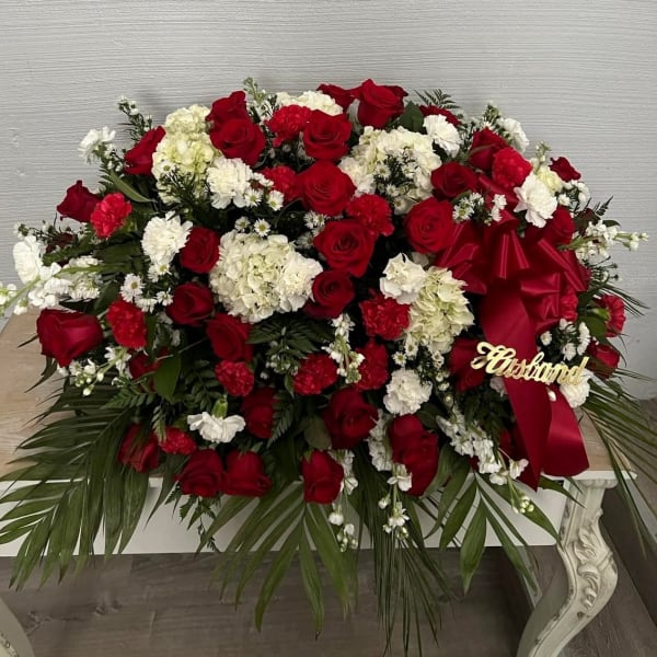 Large red and white floral arrangement with a red ribbon and gold "Husband" sign
