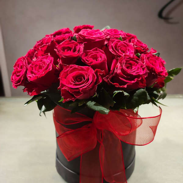 Red roses arranged in a black box with a sheer red ribbon