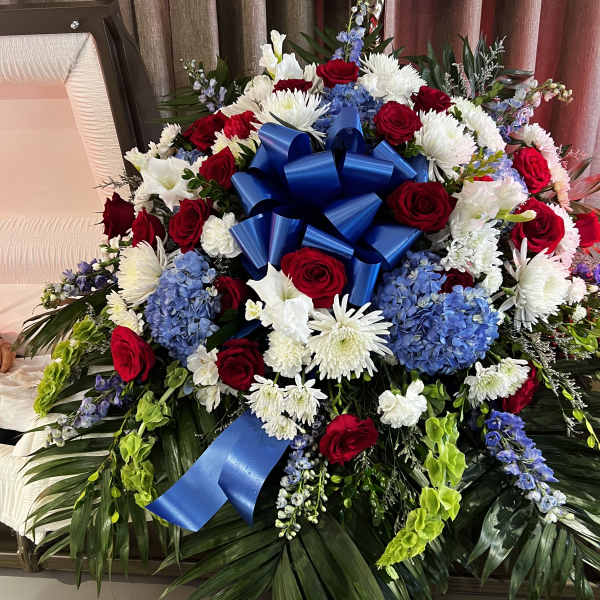 Large funeral spray with red roses, white chrysanthemums, and blue ribbon