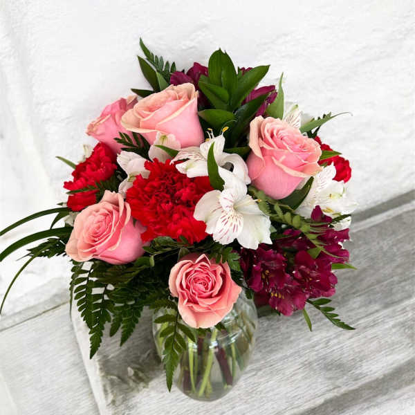 Pink roses and red flowers arranged in a glass vase