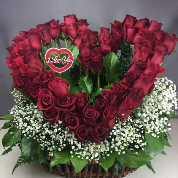 Heart-shaped red rose arrangement in a wicker basket with baby's breath